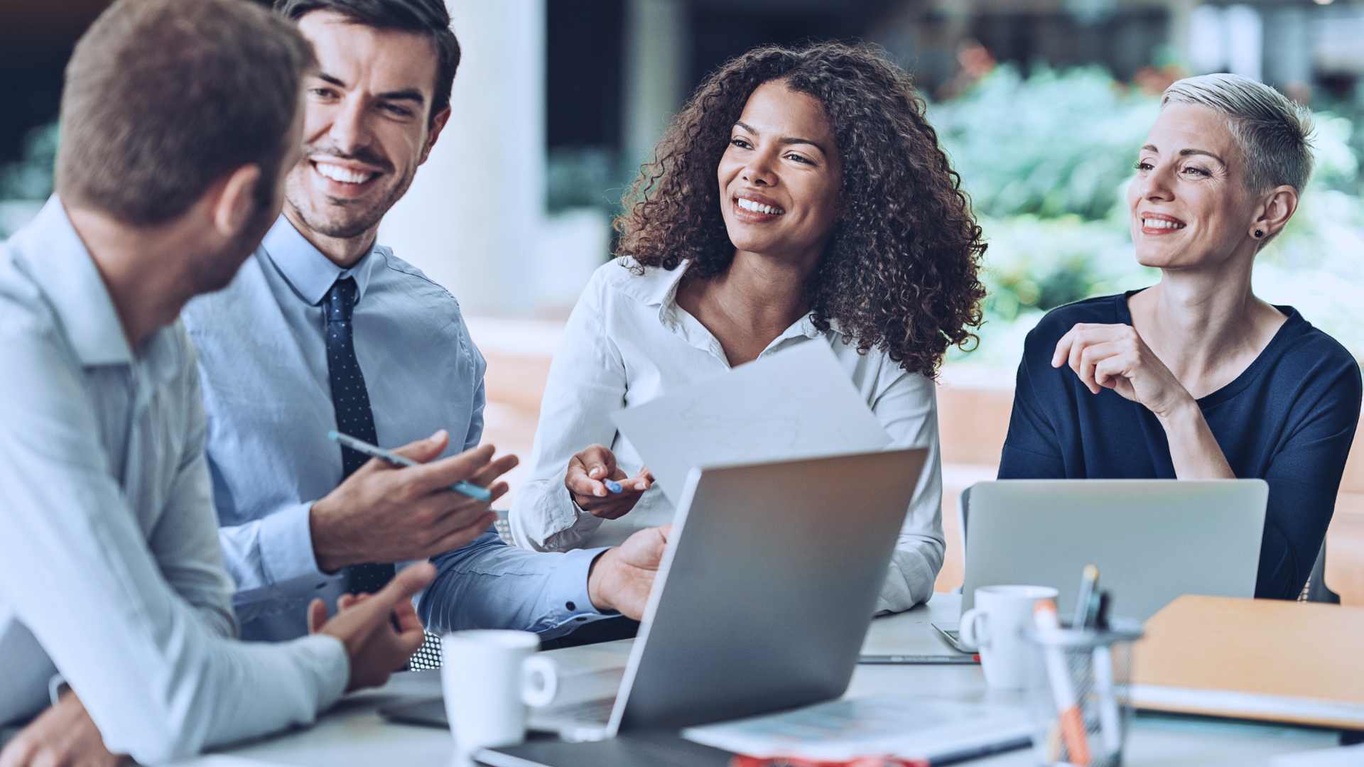 Business professionals working on their laptops and having a conversation with one another