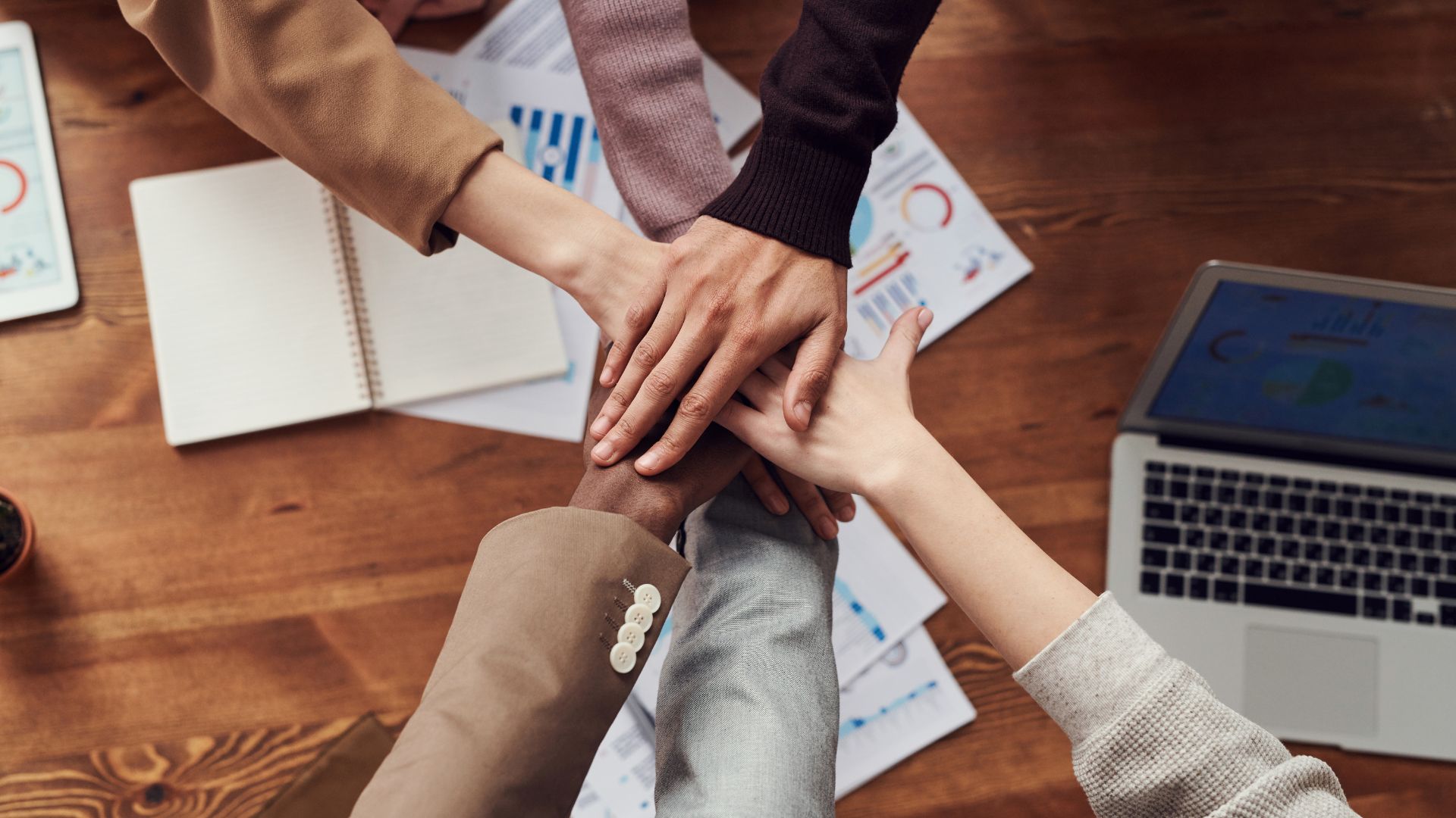 Top-down view of a group of people placing their hands together in a show of unity and teamwork