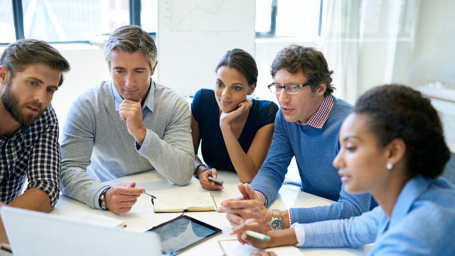 A group of professionals around a table looking at a screen together
