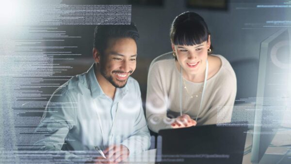 Business professionals working together on a computer with an overlay of code