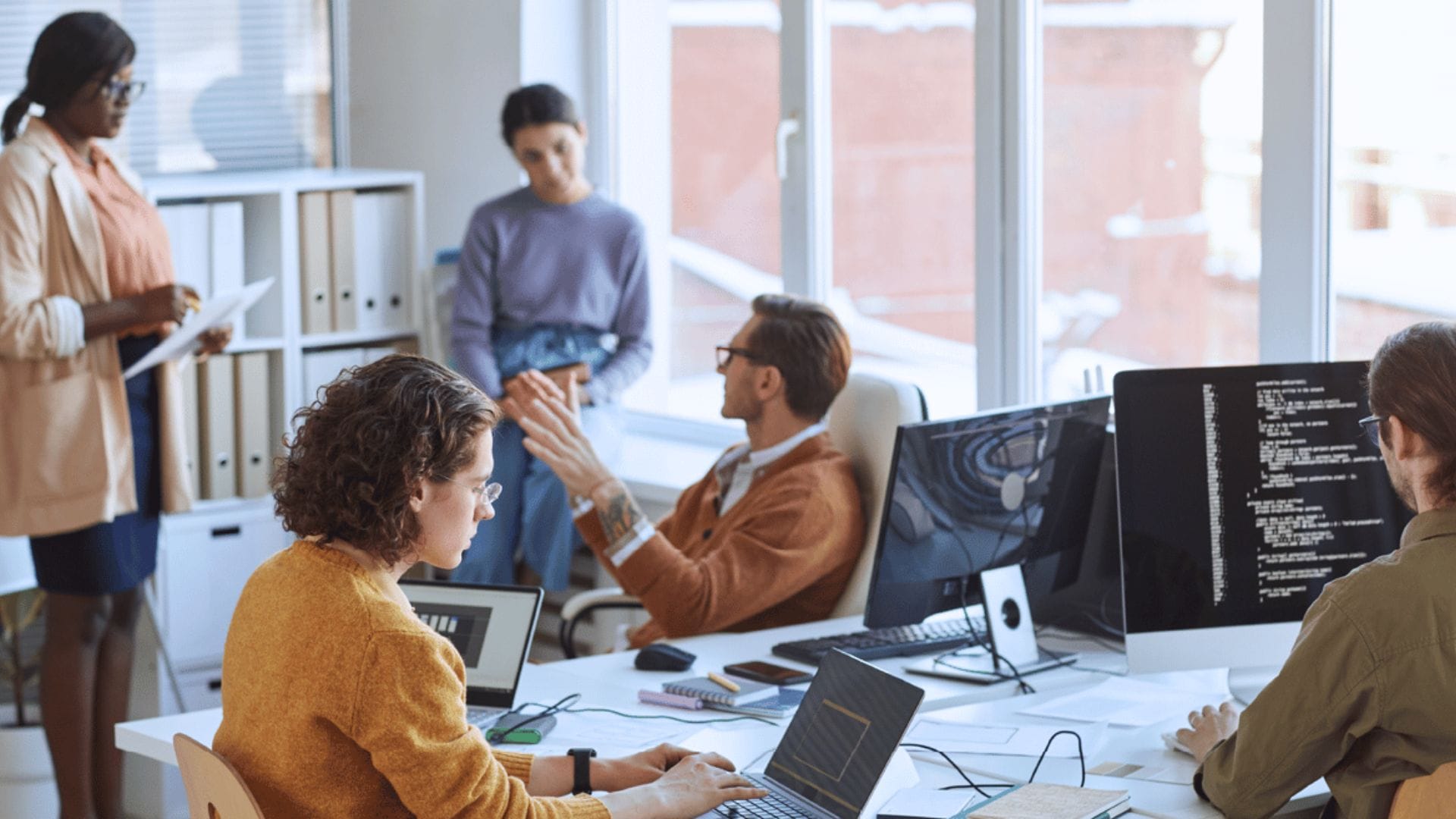 A team working and brainstorming ideas around a table of computers 