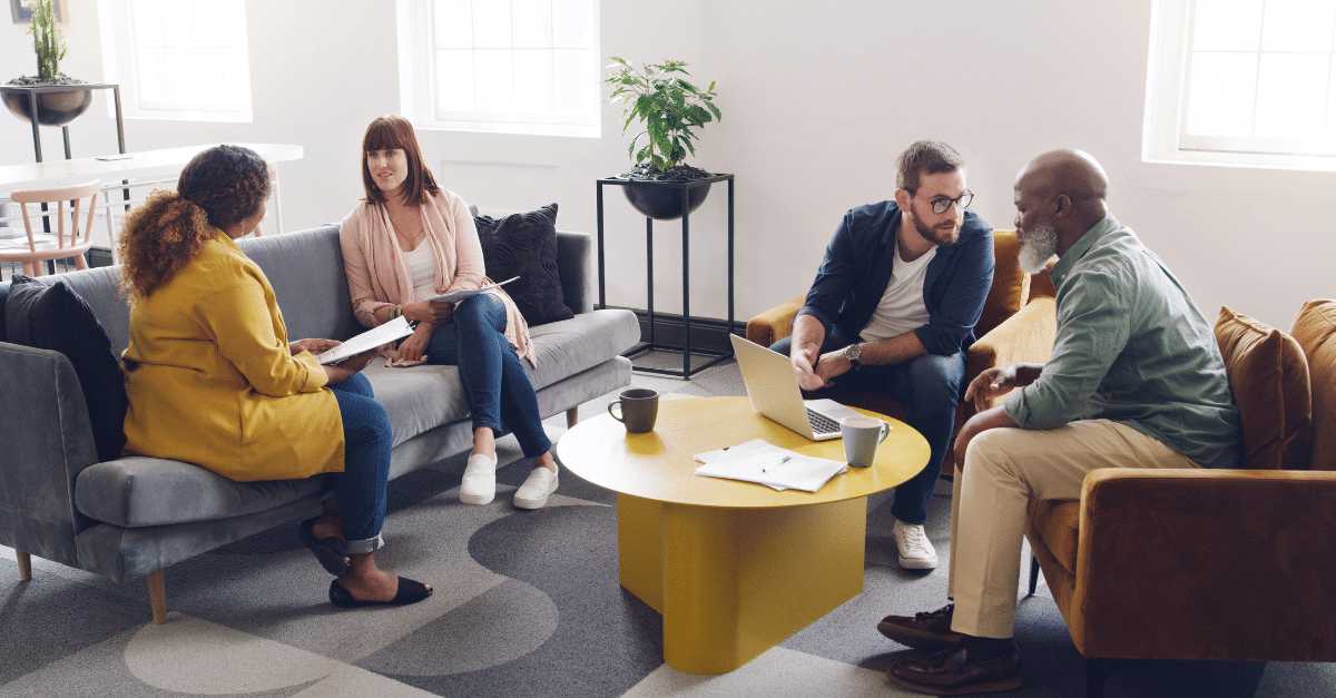 A group of cybersecurity professionals in a meeting around a coffee table