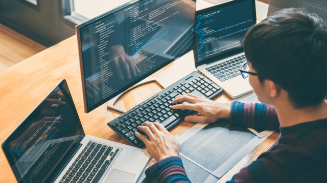 Man working at a desk with three computers