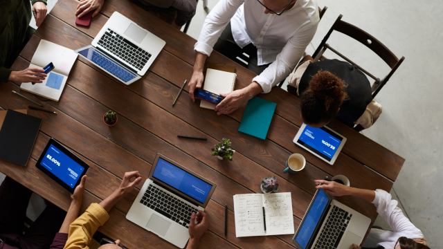 A team of professionals around a table working on their endpoint devices